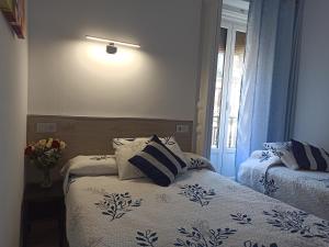 1 dormitorio con 2 camas y un jarrón de flores en Hostal Huespedes Toledo, en Madrid