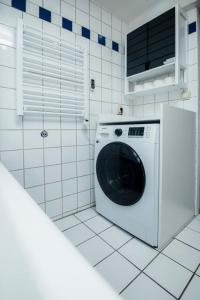 a white washing machine in a white tiled kitchen at Ferienhaus Zum Goldschmied in Rimpar