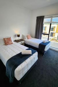 duas camas num quarto de hotel com uma janela em U Suites on Trieste Way em Paraparaumu