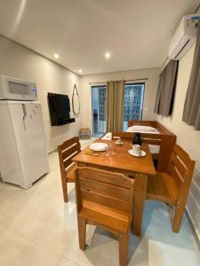 a dining room with a table and a refrigerator at Villa Licuri Boiçucanga in Boicucanga