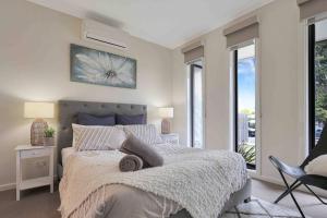 sypialnia z łóżkiem, krzesłem i oknami w obiekcie OG Spa Retreat- 3 bedroom, Spa, Central, Aircon w mieście Ocean Grove
