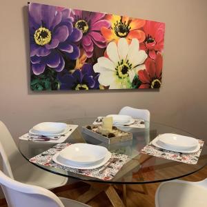 a dining room table with a flower painting on the wall at Loft l'Alessandra in Bolzano