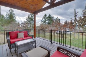 une terrasse couverte avec un canapé rouge et des chaises sur la terrasse. dans l'établissement Bigfork Cottage with Lake Views 5 Mi to Downtown, à Bigfork