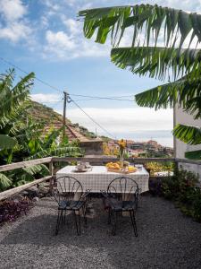 a table and chairs with a view of the ocean at Isabela House in Ponta do Sol