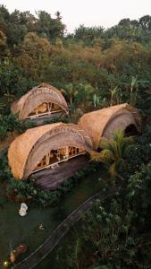 an overhead view of three small buildings with grass roofs at Sun Sang Eco Retreats in Tabanan