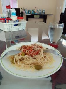 a plate of spaghetti with a fork and a glass of water at Posada Nativa Miss G in Providencia