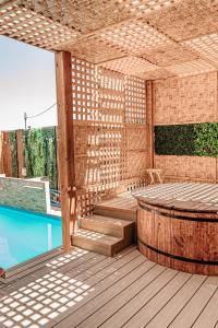 a wooden pergola with a pool and a table at 2 Cabañas para 5 Personas Oasis Pica-Matilla in Pica