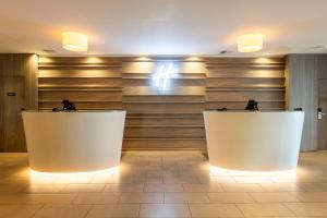 a lobby with two white tables in front of a wall at Holiday Inn - Glasgow Airport by IHG in Paisley