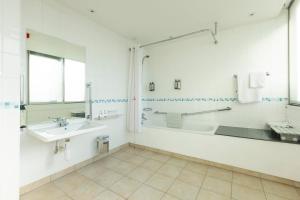 a bathroom with a tub and a sink and a mirror at Holiday Inn - Glasgow Airport by IHG in Paisley