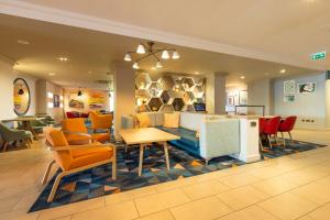 a living room with a couch and tables and chairs at Holiday Inn - Glasgow Airport by IHG in Paisley