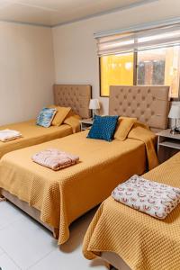 a bedroom with two beds with orange sheets and blue pillows at 2 Cabañas para 5 Personas Oasis Pica-Matilla in Pica