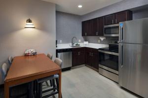 a kitchen with a table and a stainless steel refrigerator at Residence Inn Shreveport Airport in Shreveport