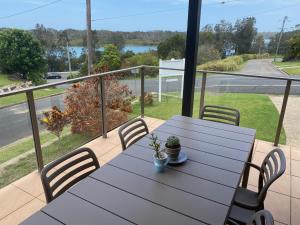 a table and chairs on a balcony with a view of a street at Riverside Rest Nambucca Heads in Nambucca Heads