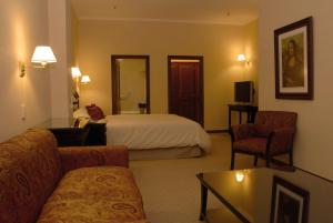 リオ・グランデにあるStatus Hotelのベッドとソファ付きのホテルルーム