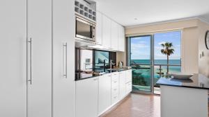 uma cozinha com armários brancos e vista para o oceano em Sea Side 112 em Mandurah