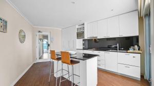 a kitchen with white cabinets and orange chairs in it at Sea Side 112 in Mandurah +4 photos
