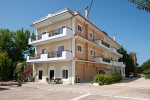 un gran edificio amarillo con balcones y mesas en Rooms Nancy, en Agios Andreas - Mesenia