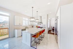 a kitchen with white cabinets and orange bar stools at Snow Valley Hideaway in Barrie