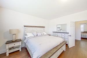 a white bedroom with a large bed and a mirror at Snow Valley Hideaway in Barrie