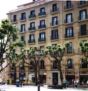 un gran edificio con árboles delante de él en Apartamento en Playa de Ondarreta, en San Sebastián