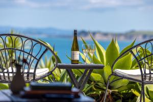 a bottle of wine sitting on a table with two glasses at The Moorings Studio Apartments in Oneroa