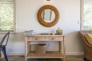 uma mesa de consola com um espelho na parede em The Moorings Studio Apartments em Oneroa