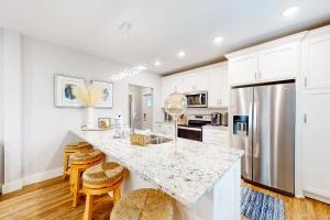 a kitchen with white cabinets and a kitchen island with stools at The Driftwood Sanctuary in Galveston