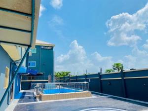 ein Gebäude mit einem blauen Zaun und einem Pool in der Unterkunft New Heights Castle Hotels in Odo Mola