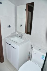 a white bathroom with a sink and a toilet at Lovely Apartment With Pool & Gym in Kenitra