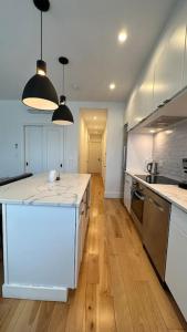 a large kitchen with white counter tops and wooden floors at Airy, modern Penthouse in a Brooklyn Brownstone in Brooklyn