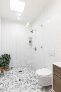 y baño blanco con aseo y ducha. en Airy, modern Penthouse in a Brooklyn Brownstone en Brooklyn