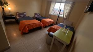 Habitación con 3 camas, mesa y ventana en Hostal la perla del sur en Quito