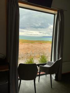 une fenêtre avec deux chaises et une vue sur le désert dans l'établissement “The Cliffs” Humpridge View Motels, à Tuatapere