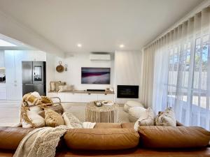 a living room with a large couch and a tv at Boho Beach House in Rosebud