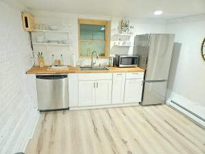 a kitchen with white cabinets and a stainless steel refrigerator at 2-Bedroom in the Heart of Denver in Denver
