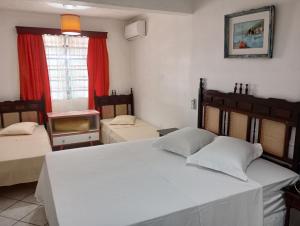 Un dormitorio con una gran cama blanca y una ventana en Pousada Kanaxuê en Barra Velha