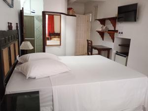 a bedroom with a white bed with two pillows at Pousada Kanaxuê in Barra Velha
