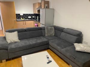a gray couch in a living room with a kitchen at Eaglet 2 Bedroom Luxury Home near Etihad Staduim in Manchester