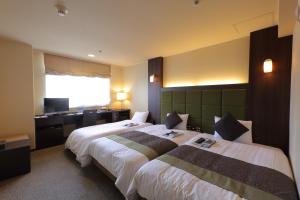 a hotel room with two beds and a desk at Hotel Binario Saga Arashiyama in Kyoto