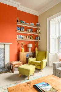 a living room with orange walls and a green chair at 5-BR 3-BTH Newington Apartment - Modern & Spacious in Edinburgh