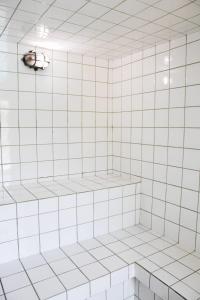 una ducha de azulejos blancos con una luz en el techo en Hotel Manoah en Socorro