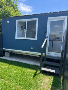 a blue tiny house with a window at Sweet Cute blue tiny home with Pool and 2 minute drive to the beach in Wollongong