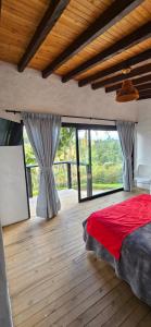 Schlafzimmer mit einem roten Bett und großen Fenstern in der Unterkunft La escondida in Guarne