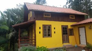 a yellow house with a brown roof at Chalé Sol da Montanha em Termas do Gravatal - SC in Gravatal