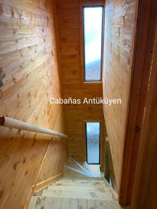 una escalera en una cabaña de madera con 2 ventanas en CABAÑAS ANTU KUYEN en Pichilemu
