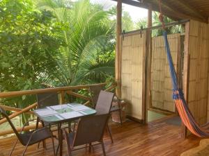 a porch with a table and chairs and a hammock at Villas Solar in Santa Teresa Beach