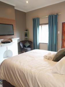 um quarto com uma grande cama branca e uma cadeira em Precious Estates Pearls em Zeerust