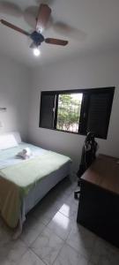 um quarto com uma cama, uma ventoinha de tecto e uma janela em Casa próxima ao centro! em Uberaba