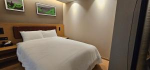 ein Schlafzimmer mit einem weißen Bett und zwei Bildern an der Wand in der Unterkunft Elbon The Stay Haeundae 엘본더스테이 해운대 in Busan