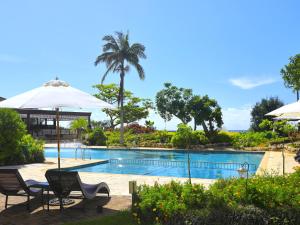 a swimming pool with two chairs and an umbrella at Hotel Breezebay Marina in Miyako-jima
